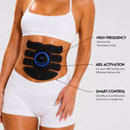 A woman wearing a white sports bra and shorts with a black abdominal exercise pad on her stomach. The pad has a blue digital display and is shown with callout lines and text explaining features like high frequency, abs activation, and smart control.